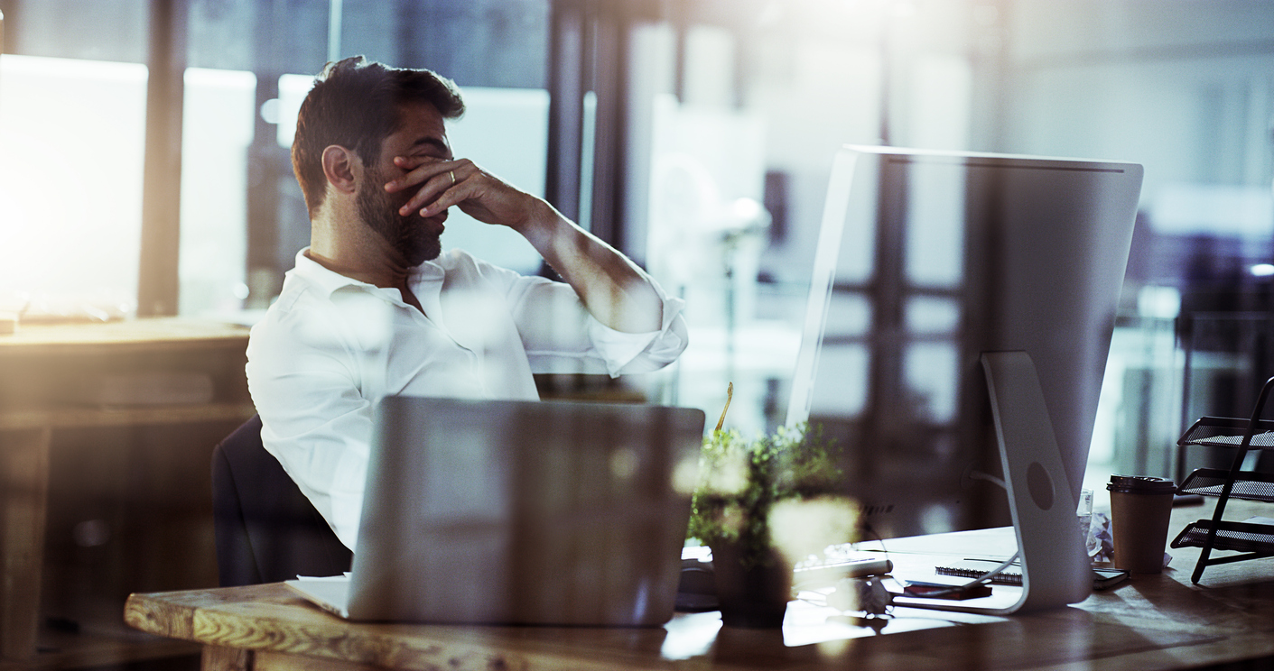 stressed man at desk in front of computer screen - bad bookkeeping risks