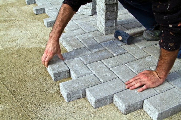 Why deregistering for VAT could make sense - male hand laying brick paving