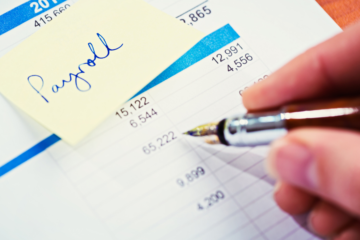 pen, paper and sticky note saying Payroll