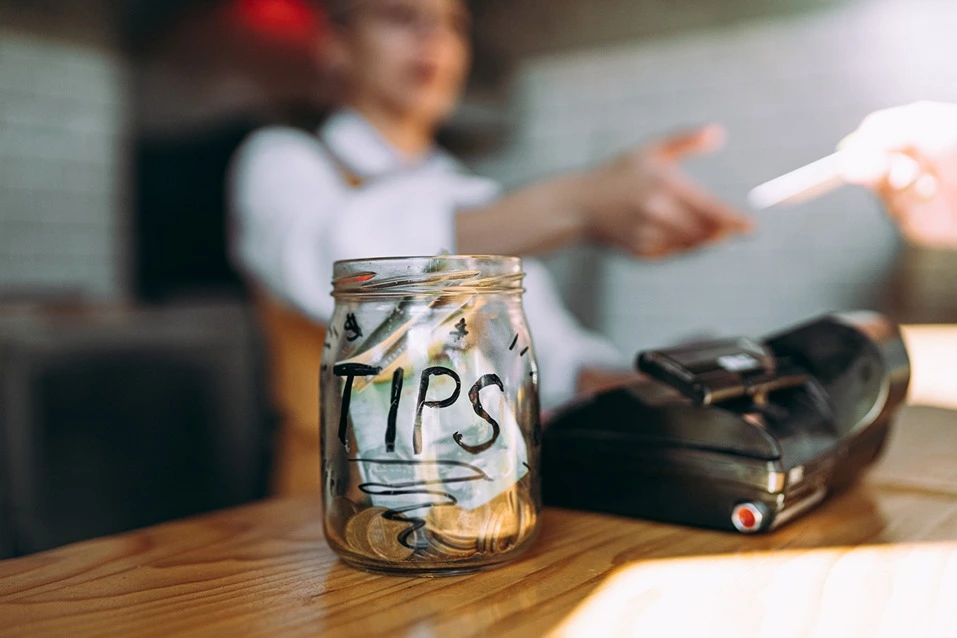 A glass jar labelled ‘tips’ on a wooden table