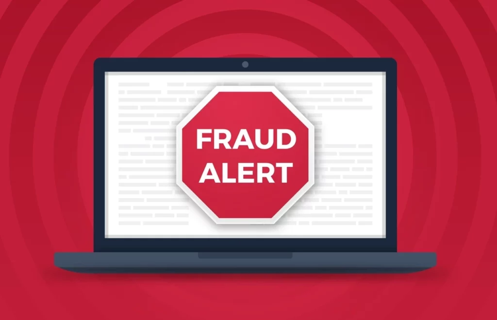 White computer screen against a red background, with a red octagonal sign on the screen saying ‘Fraud Alert’